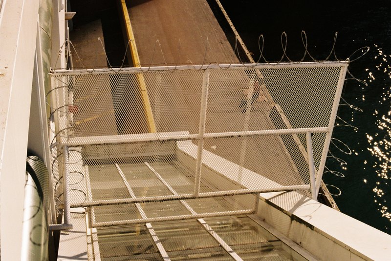 A metal stairway and wire gate above dark water.